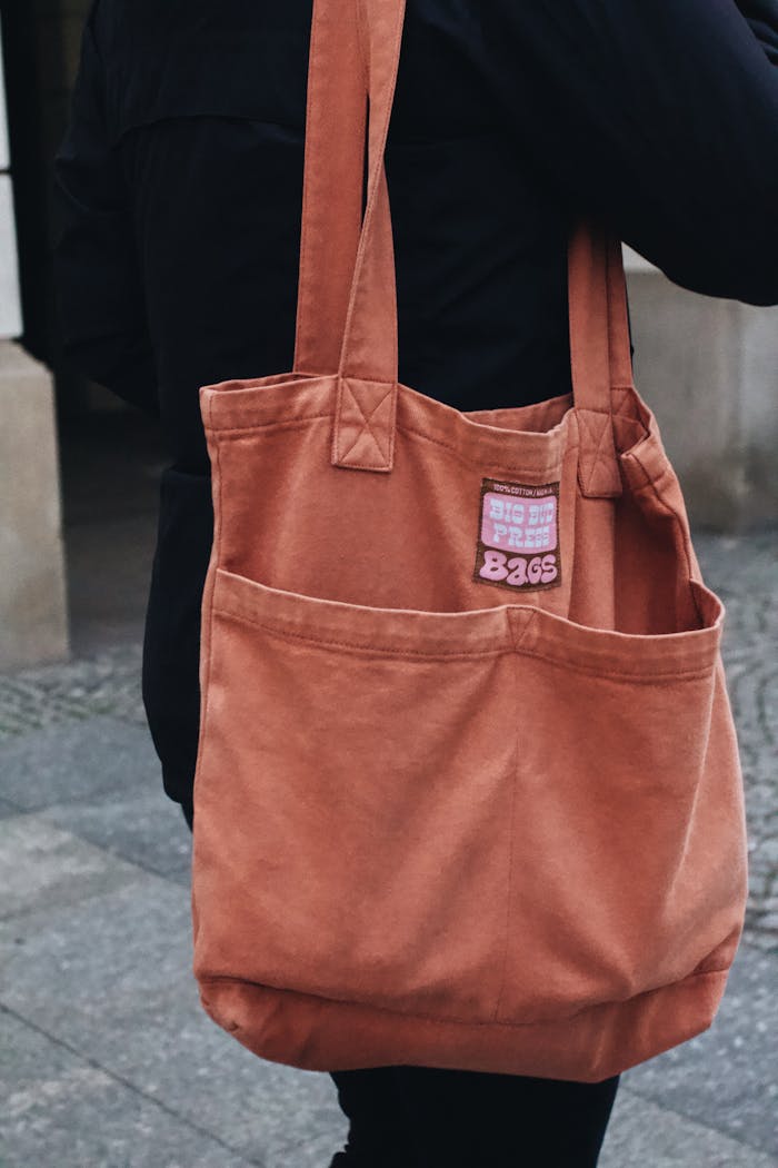 Close-up of a fashionable canvas tote bag on a pedestrian in Warsaw's urban setting.
