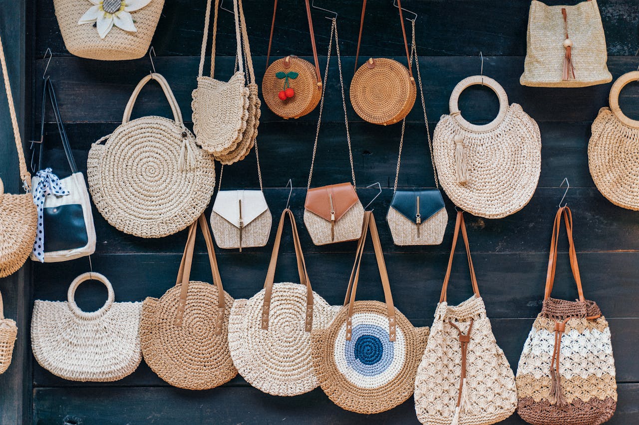 A collection of handcrafted rattan and straw bags displayed artistically on a wall, showcasing stylish and trendy designs.